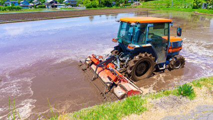 夏の青空と田植えをするトラクター