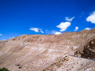 Sand mountain under blue sky with clouds