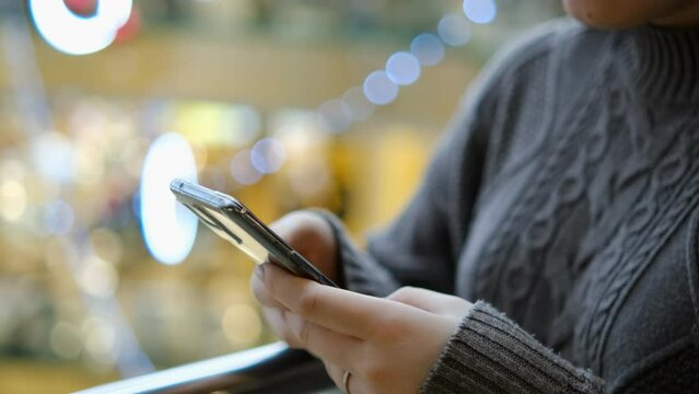 Shopping center. Moll. Finger of woman touching scroll page app on mobile phone. Browsing movie video in the internet library to watch film online.