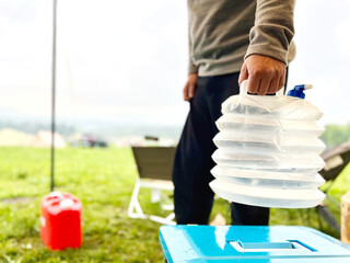 キャンプ場で男性が持った折りたたみ水タンク