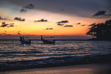 two fishing boats on the background of the sunset on the shore of Phuket Thailand