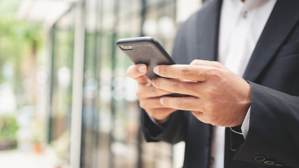 Close up businessman typing on smart phone and smilling
