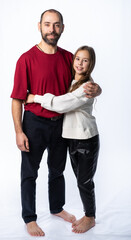 dad hugs daughter by the shoulders in the studio. a man in a burgundy-red T-shirt, a girl in a white sweatshirt. isolated white background