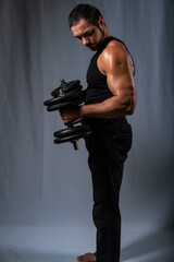 Fototapeta na wymiar muscular man. athlete trains with heavy dumbbell. studio portrait