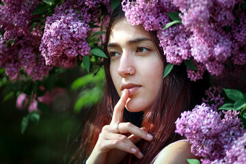 Beautiful young woman in flowers of lilac