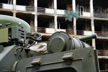 Close up of a green military truck on the background of a destroyed building. Modern technologies of military transport equipment