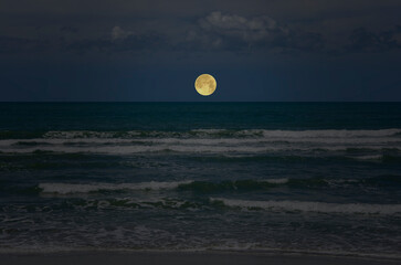 Beautiful full moon ove white waves in blue sea