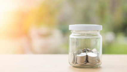 Closeup of coins in the jar on a wooden table. saving money for the future, budget, savings, financial planning, accounting, tax, and investment.