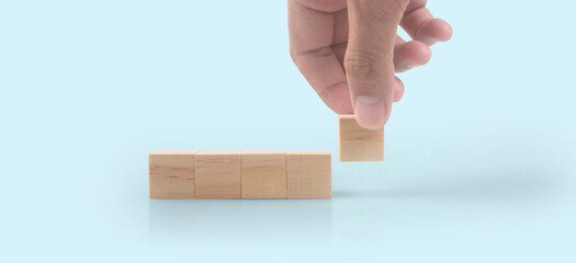 Hand putting wooden cube blocks