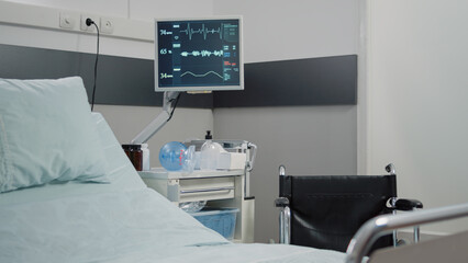 Close up of heart rate monitor for reanimation and intensive care in empty hospital ward. Nobody in emergency room with medical equipment, oxygen tube and instruments for resuscitation
