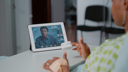 Close up of patient using video call on digital tablet to talk to man while laying in hospital ward bed. Person talking to friend on online video conference on device. Remote communication