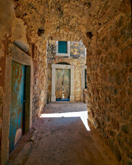 An arched stone gallery leads to a small, sunny square. Pirg;i town, Chios island, Greece