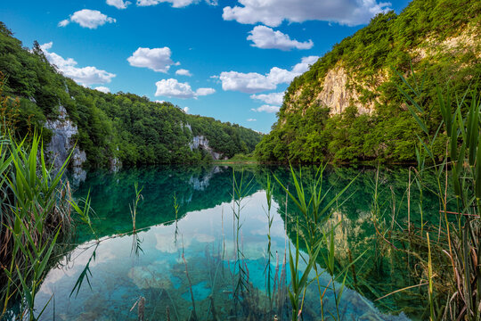 Plitvice, Croatia - Reflecting Plitvice Lakes National Park on a bright summer day with crystal clear turquoise water, blue sky and clouds and green summer foliage