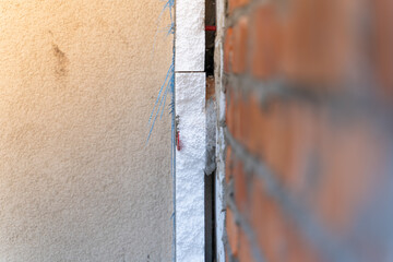 The sequence of insulation of the facade of a private house. The foam is glued to the wall with an...