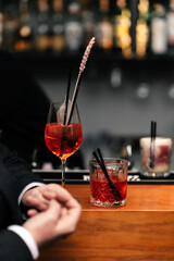 on the bartenders table are two glasses of red cocktails into which the drink is poured. Orange juice, alcohol. On a dark background