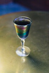 black lemonade cocktail drink in vintage iridescent glass on muted gold brass table