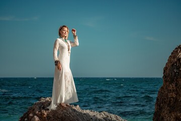 Woman in bohemian clothing on beach at sunset. Boho style for fashionable look on resort. Middle aged well looking woman in white dress and boho style braclets. Summer fashion