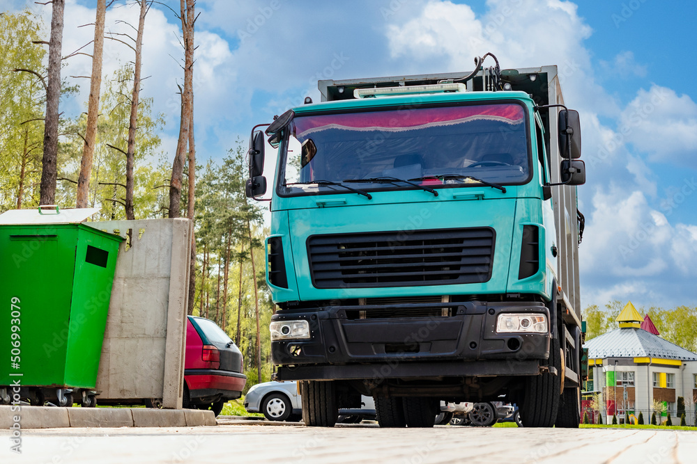 Leinwandbilder A garbage truck picks up garbage in a residential area. Loading mussar in containers into the car. Separate collection and disposal of garbage. Garbage collection vehicle.