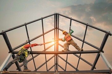 Construction workers wear safety belts during work on building roof structure at construction site