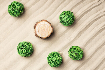 sand texture with waves on which there is a round pine stump, next to it are green wicker balls