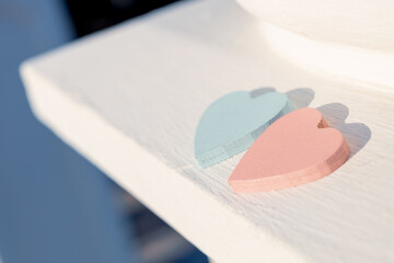 two hearts made of blue and red wood on the edge of a white concrete surface