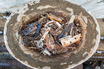 Plastic bucket with scrap metal. Recovered fittings of old wooden windows