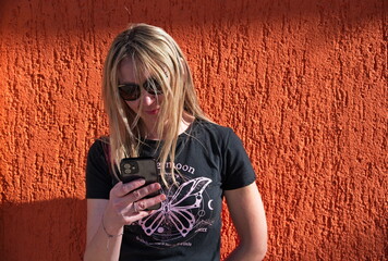 Portrait of mature woman against orange background using mobile phone