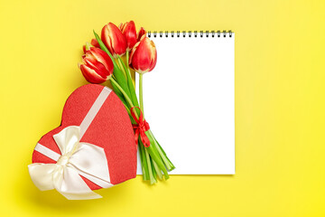 Bouquet of red tulips, gift box heart, notepad on yellow background Top view Flat lay Holiday greeting card Happy moter's day, 8 March, Valentine's day, Easter concept Copy space Mock up