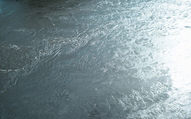 Flowing blue river on sunny day. Top view wide stream of water with sun glare outdoors