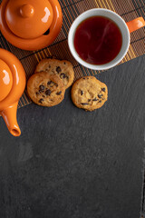 a cup of tea and cookies with chocolate, photo from above on a dark background with space for text