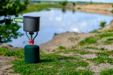 Gas tourist burner with cook pot and background river 