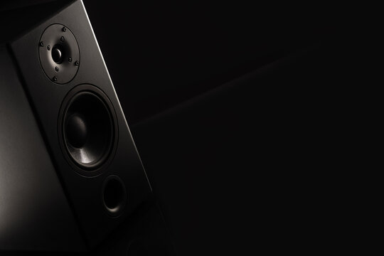Stereo sound speakers closeup on black background with copy space. Contrast, accent lighting from the side