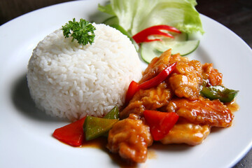 Chicken fillet fried in flour cooked with sweet and sour pepper seasoning. Served with white rice. plus a garnish of parsley, fresh lettuce and cucumber.