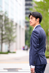 Fototapeta premium ビジネス街で遠くを見つめるビジネスマン