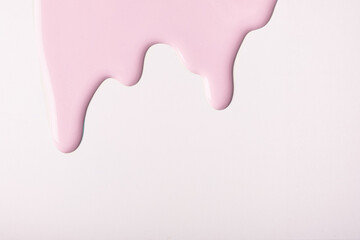 Light pink liquid drops of paint color flow down on white background. Abstract pearl backdrop with rose fluid pattern.