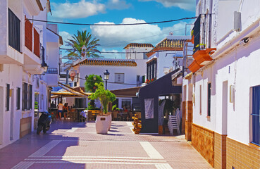 Zahara de los Atunes, Spain - June 9. 2016: Idyllic quiet sleepy atlantic coastal town with white houses, pedestrian street, restaurant bar, blue summer sky