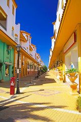 Fototapeta premium Zahara de los Atunes, Spain - Beautiful atlantic coastal spanish town, empty pedastrian street, bright yellow colorful house facades, clear blue sky
