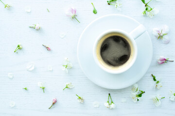 coffee and flowers on white desk, flat lay, top view. espresso, cup of black coffee and floral...