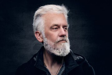 Studio shot of handsome elderly man with modern hairstyle dressed in black attire.