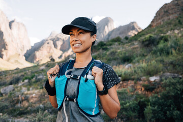Portrait of a smiling woman in hiking attire looking away while standing in the valley