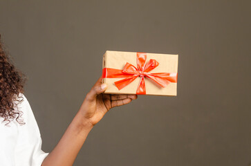closeup of female hand holding gift box isolated over gray background
