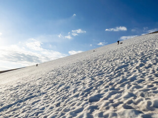 people walking on snow in high mountains in may