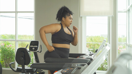 Fat black African american healthy woman, person, running or jogging on treadmill for diet, and training in gym or fitness center in sport and recreation concept. Lifestyle activity. Losing weight