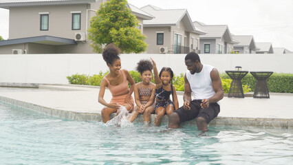 Group of relaxed black african american family, dad, mother and daughter playing by the swimming...