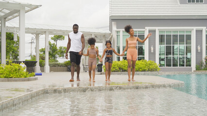 Group of relaxed black african american family, dad, mother and daughter playing by the swimming...