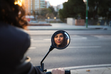Young and beautiful woman with dark and curly hair is sightseeing in Seville. She is reflected in...