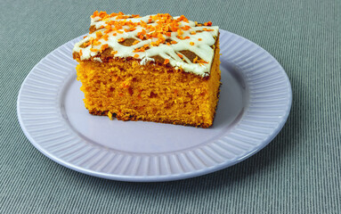 a piece of carrot cake on a plate on a tablecloth