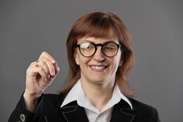 Woman in office suit writing with marker on screen or board