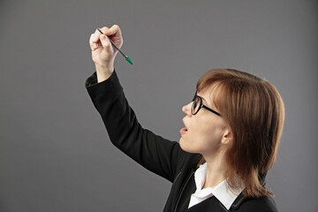 Woman in office suit writing with marker on screen or board