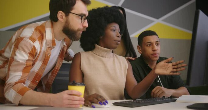 Colleagues come to woman to look together in monitor at desk
